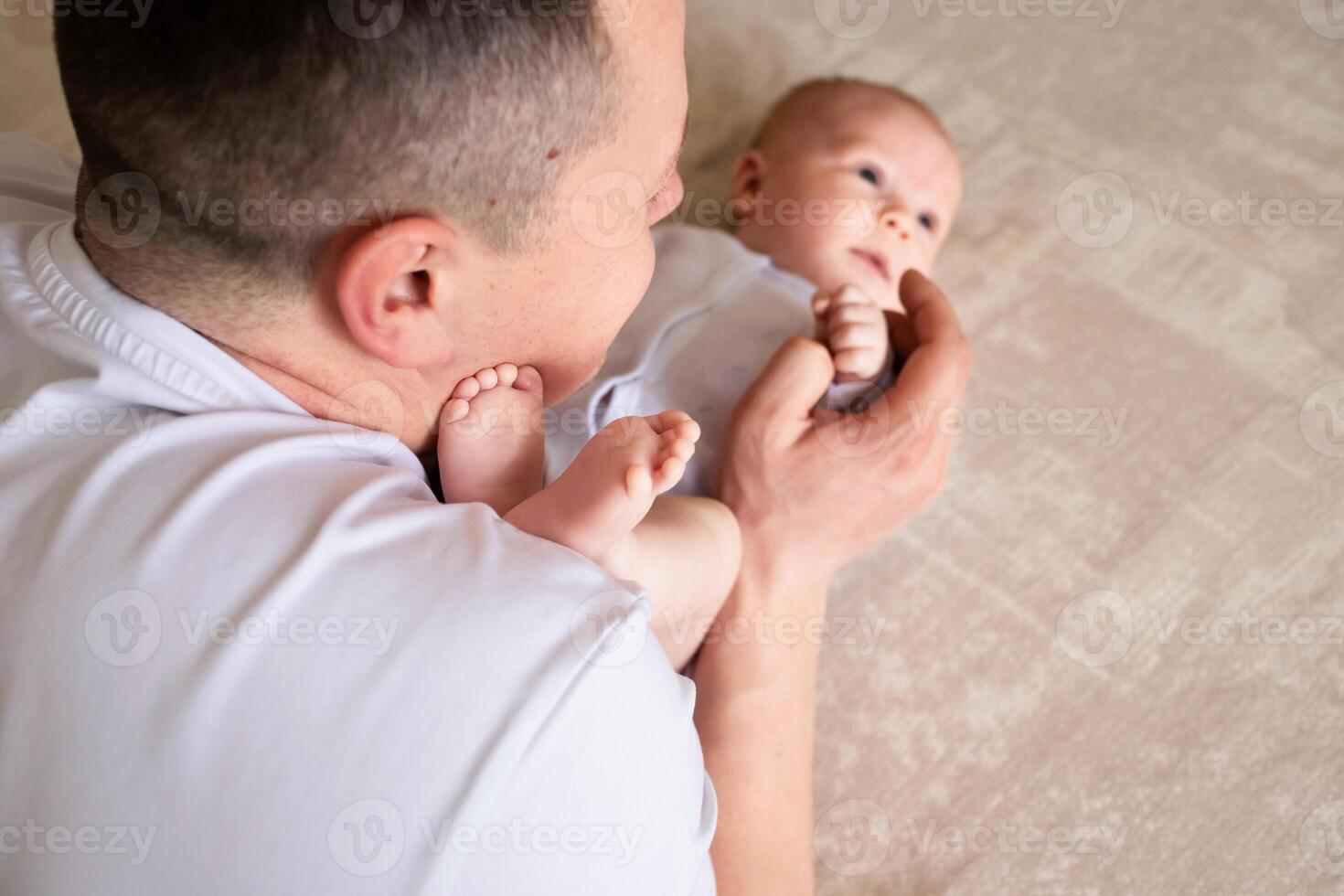 close-up dad plays with a small child at home on the bed. parent hugging a small child. family concept photo
