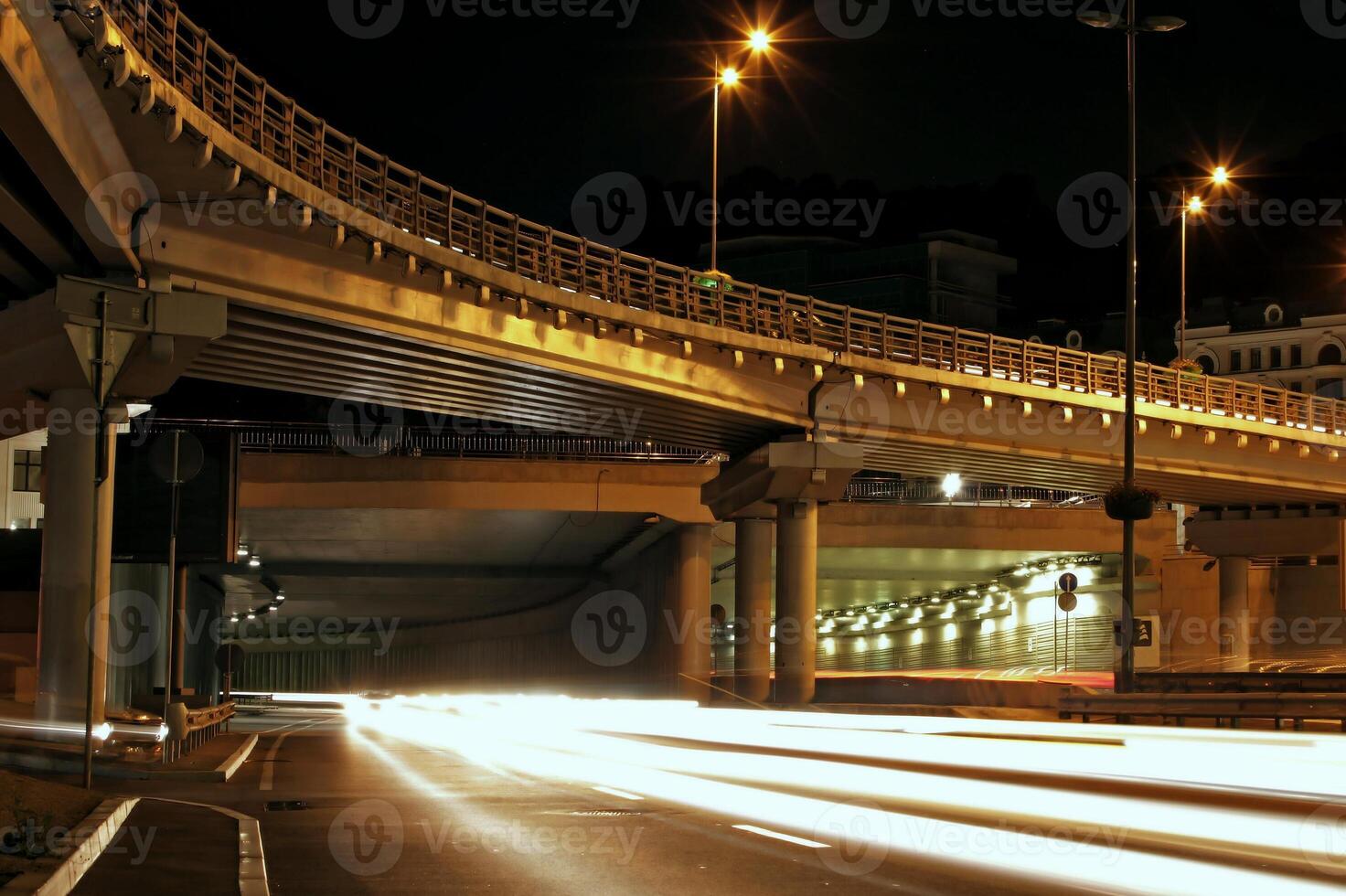 Vehicles headlights traces under road bridge at night time photo