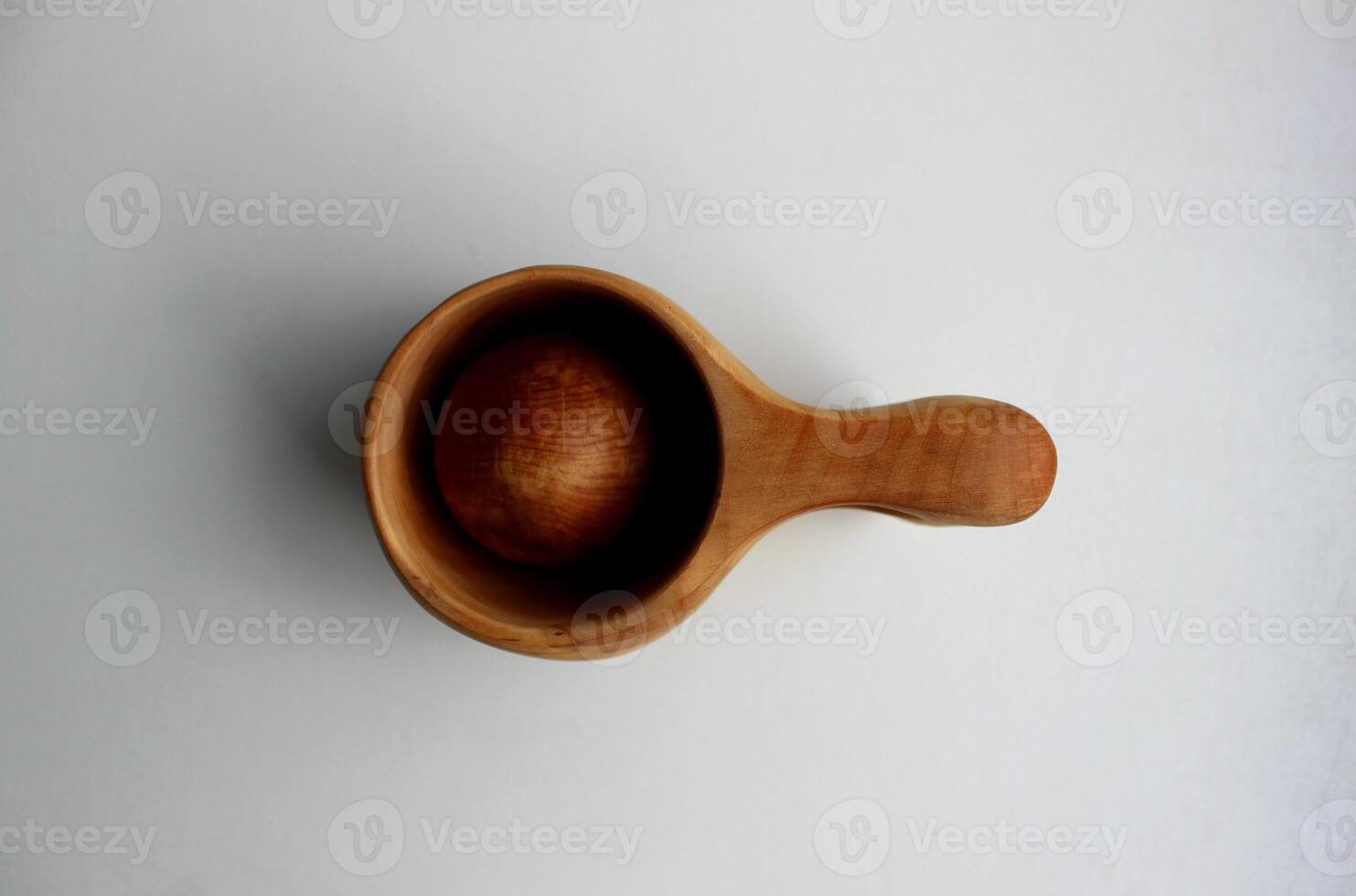Carved from birch drinking cup for bushcrafters with a round wooden ball on white surface top view photo