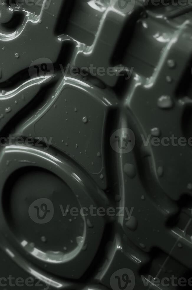 Droplets on a dark plastic surface with depressed curved lines and circle pattern close up angle view photo