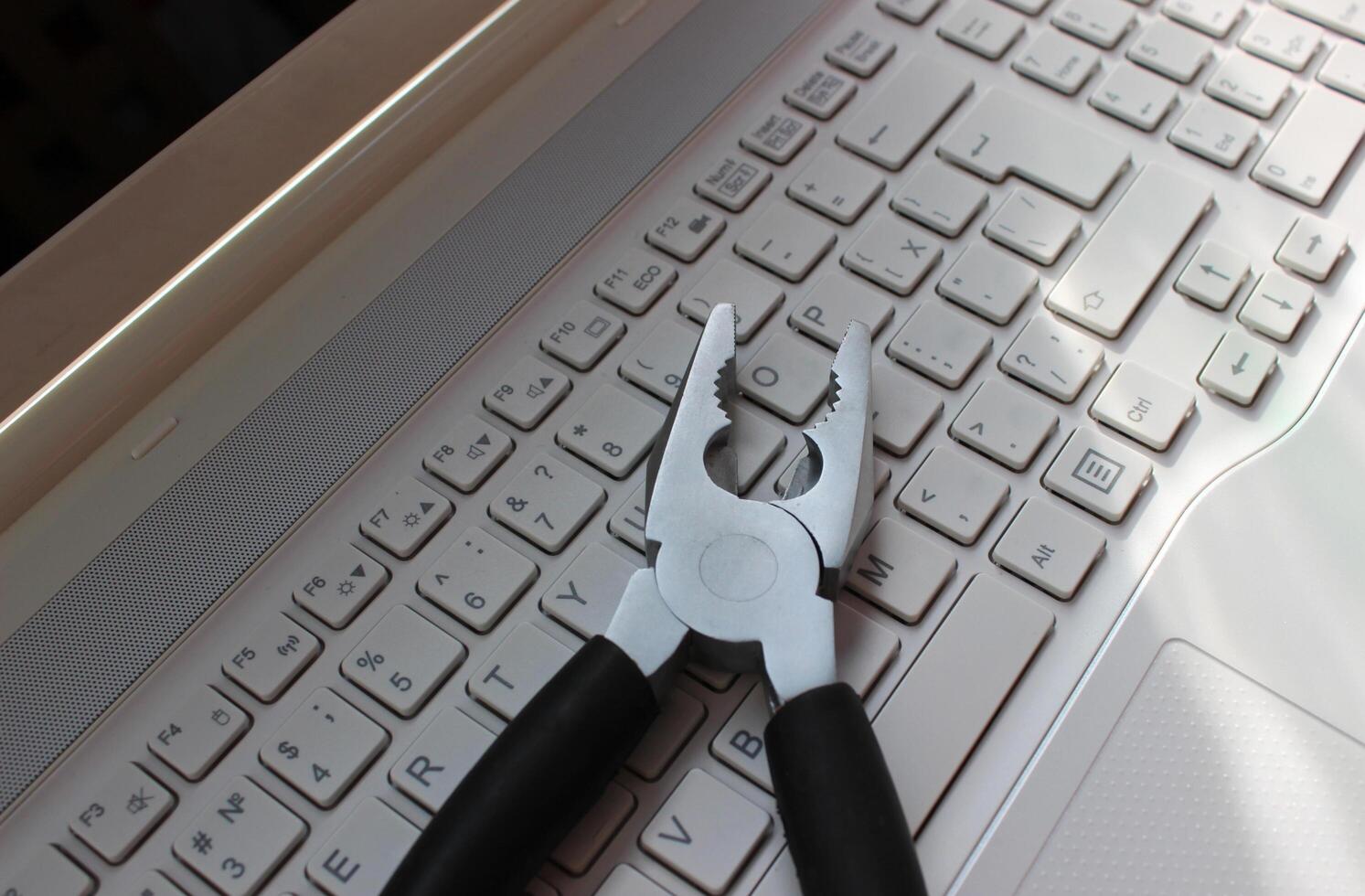 Computer Repairing Concept. Steel Pliers On Laptop Keyboard Angle View photo