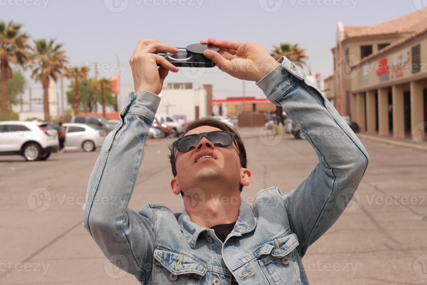 Young Man Looking at the Sun and taking photos During a Solar Eclipse using a Black Obsidian Stone