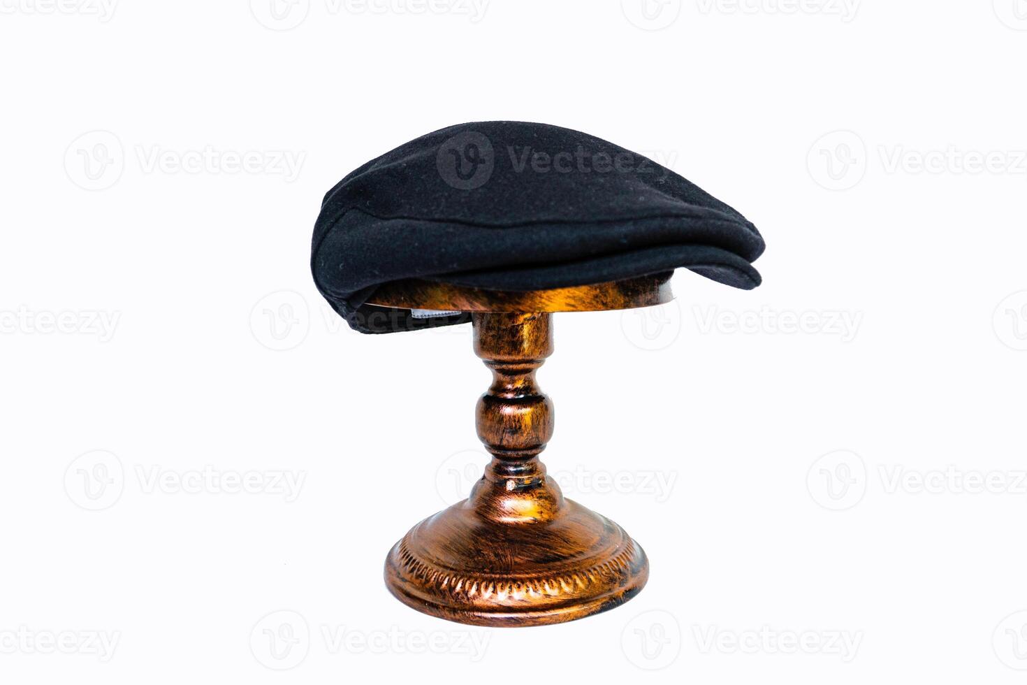 Concept photo of a classic flat cap or scally cap made of warm wool. Classic black hat mounted on bronze mannequin head on white studio background