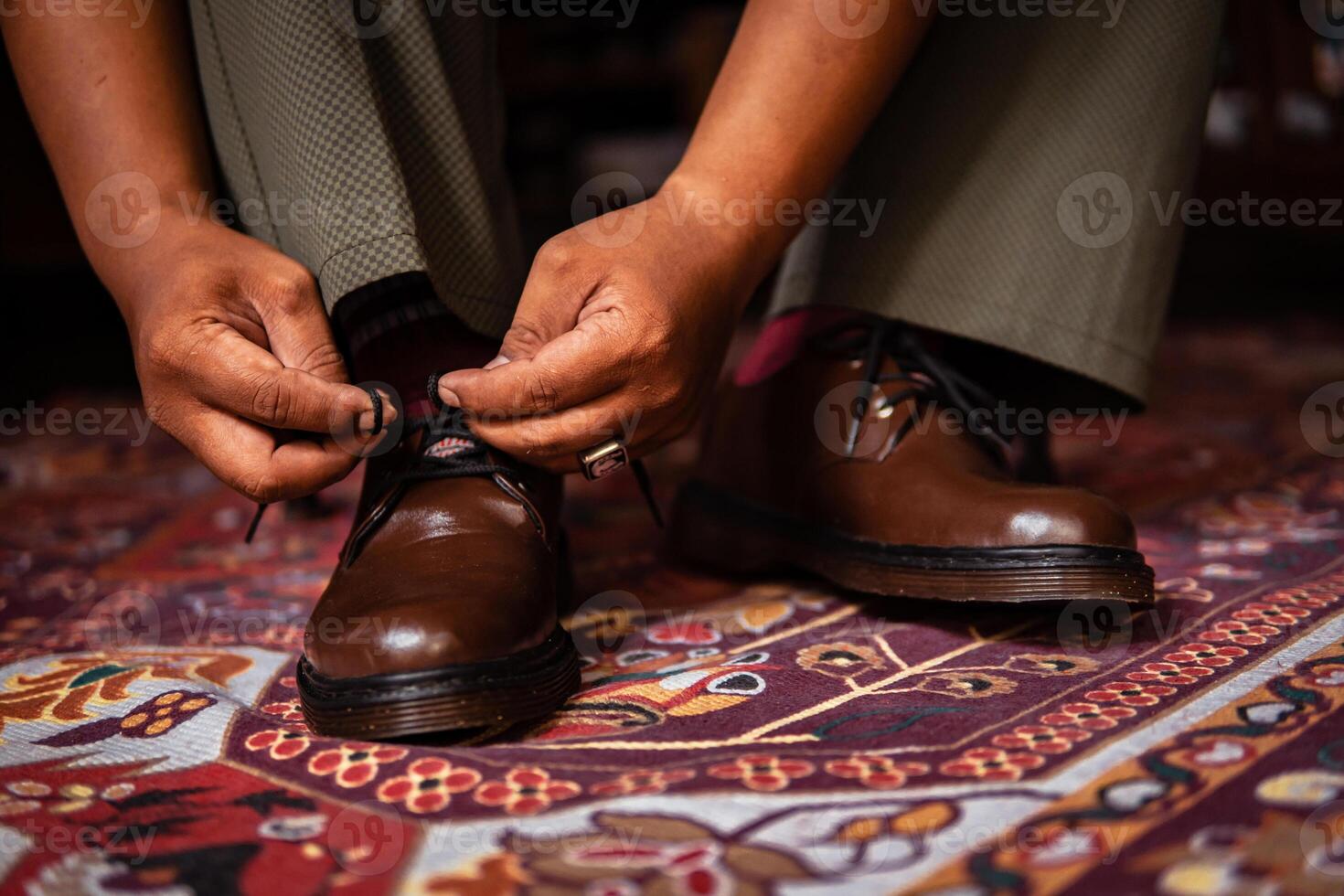 Close-up of a product concept photo of 3-hole boots made of genuine leather. Vintage shoes worn indoors on a classic red carpet. Shiny and elegant brown boots on the Turkish red carpet