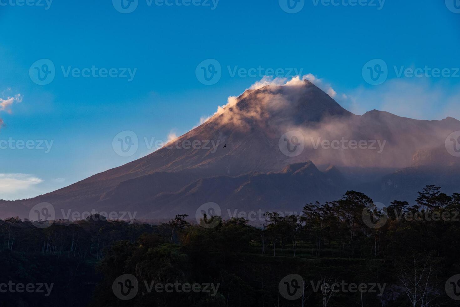 Panorama of Mount Merapi at dusk is very clear with the blue sky and green forest in the foreground with a ravine where cold lava flows. The landscape of Mount Merapi is truly enchanting and charming photo