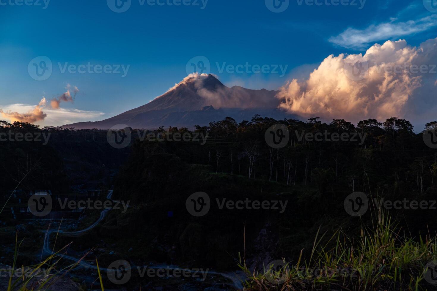 Panorama of Mount Merapi at dusk is very clear with the blue sky and green forest in the foreground with a ravine where cold lava flows. The landscape of Mount Merapi is truly enchanting and charming photo