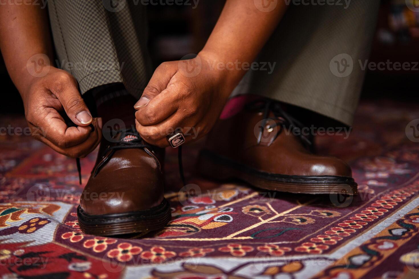 Close-up of a product concept photo of 3-hole boots made of genuine leather. Vintage shoes worn indoors on a classic red carpet. Shiny and elegant brown boots on the Turkish red carpet