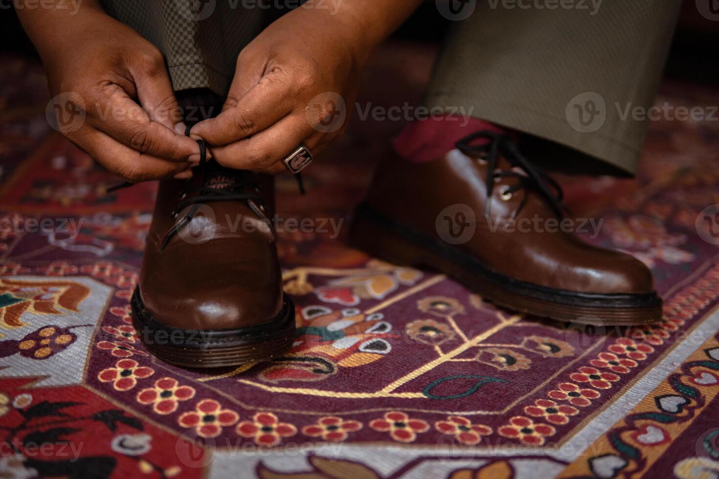 Close-up of a product concept photo of 3-hole boots made of genuine leather. Vintage shoes worn indoors on a classic red carpet. Shiny and elegant brown boots on the Turkish red carpet