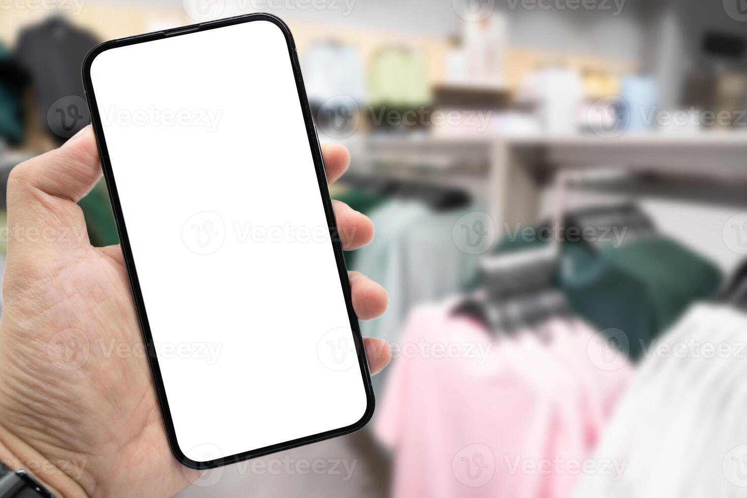 Hand holding blank screen smartphone for copy space on blurred clothing store. e-commerce app shopping mockup. social media, payment and shopping online concept. fashion and technology. photo