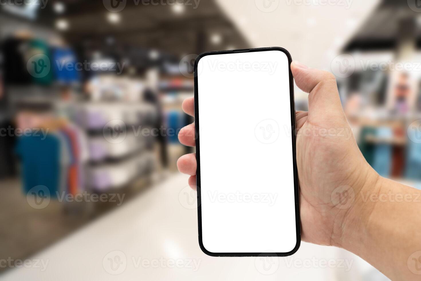 Hand holding blank screen smartphone for copy space on blurred clothing store. e-commerce app shopping mockup. social media, payment and shopping online concept. fashion and technology. photo