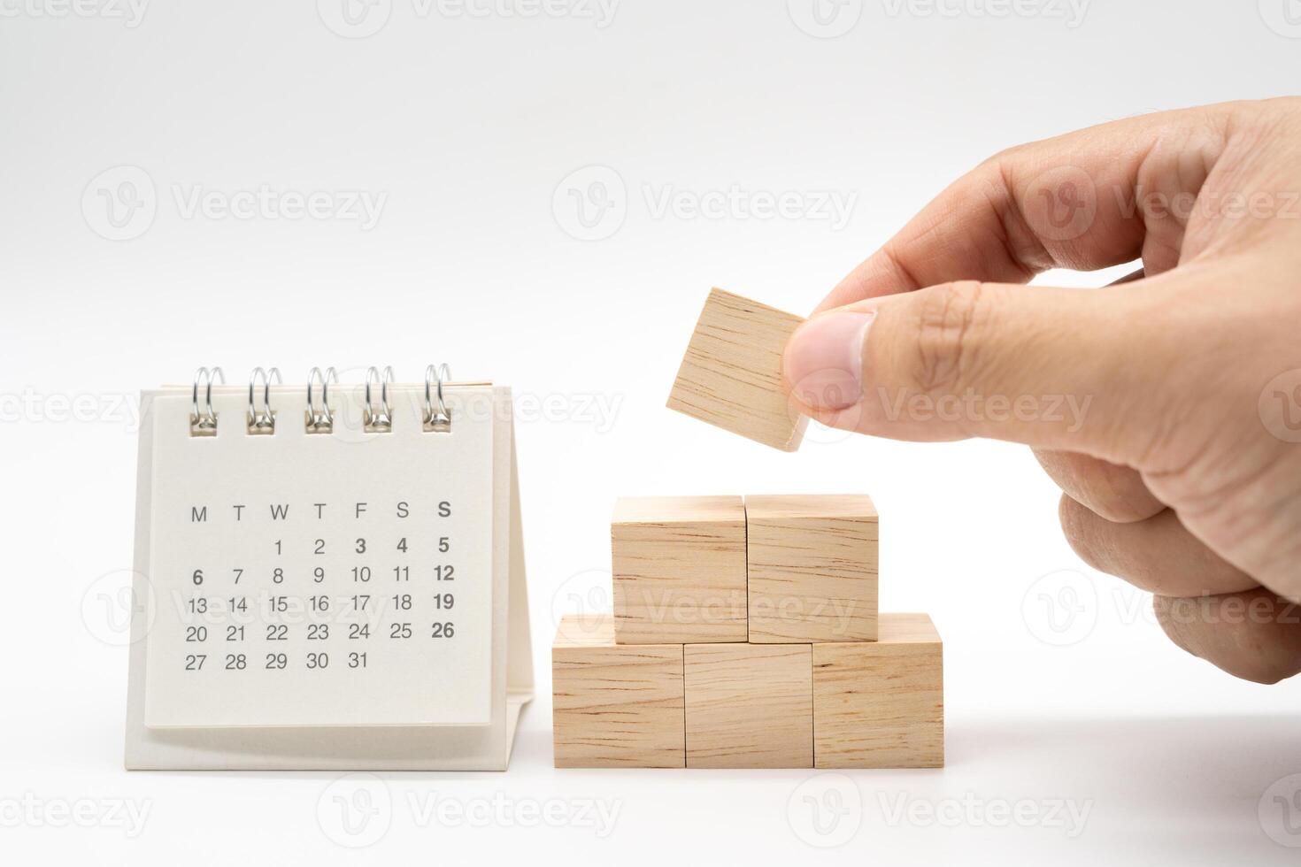 Hand putting and stacking blank wooden cubes on white background with copy space for input wording and infographic icon. Wooden blocks with Calendar. photo