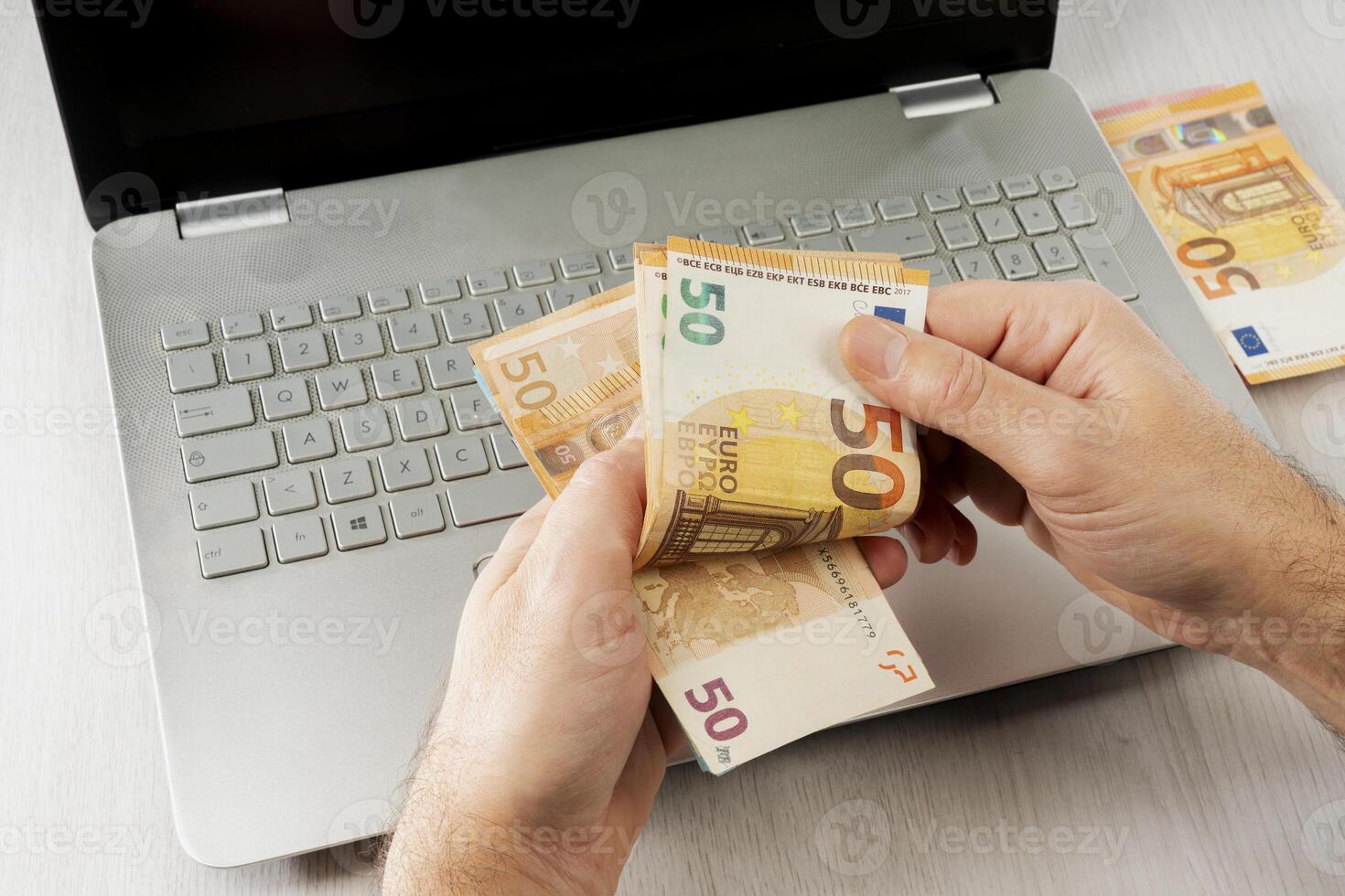 Businessman man with euro money in his hands is working on a computer keyboard photo