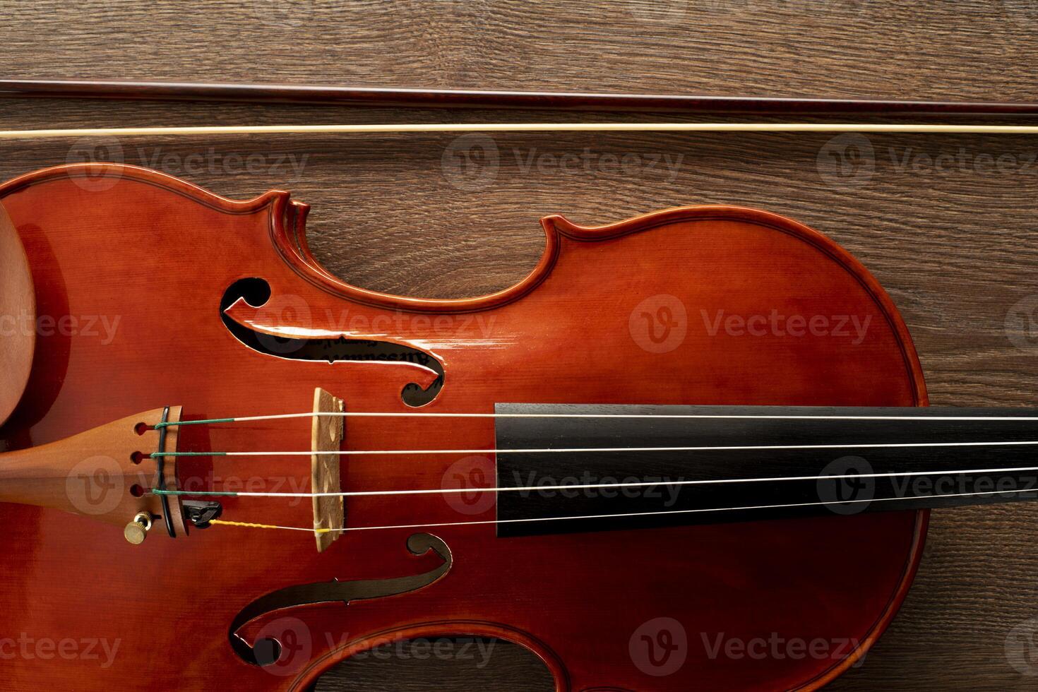 A close up of a violin with a bow on a wooden background photo