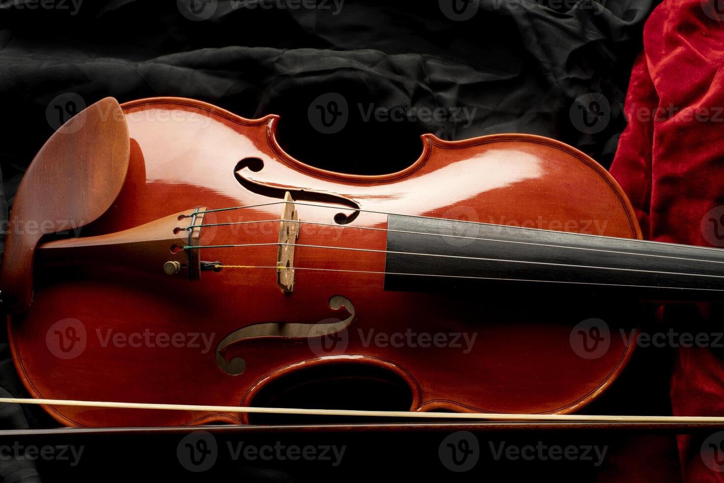 Close up of a violin with bow on a background of black and red fabrics photo