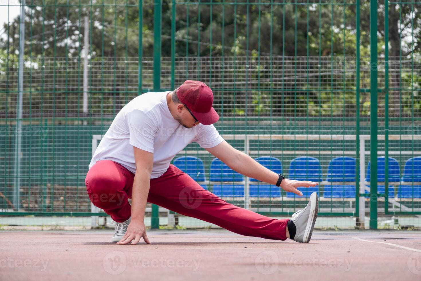 Athletic bearded man warms up before workout at the stadium photo