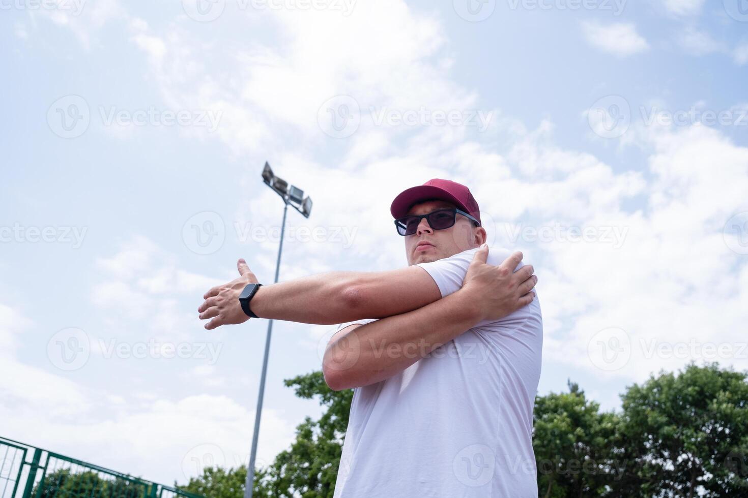 Athletic bearded man warms up before workout at the stadium photo