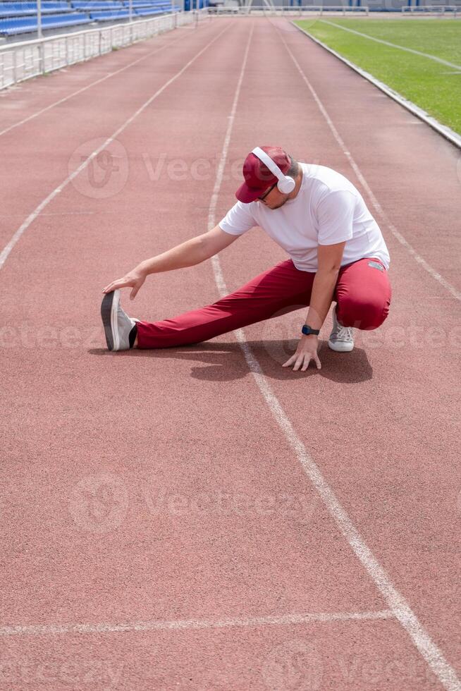 Athletic bearded man warms up before workout at the stadium photo
