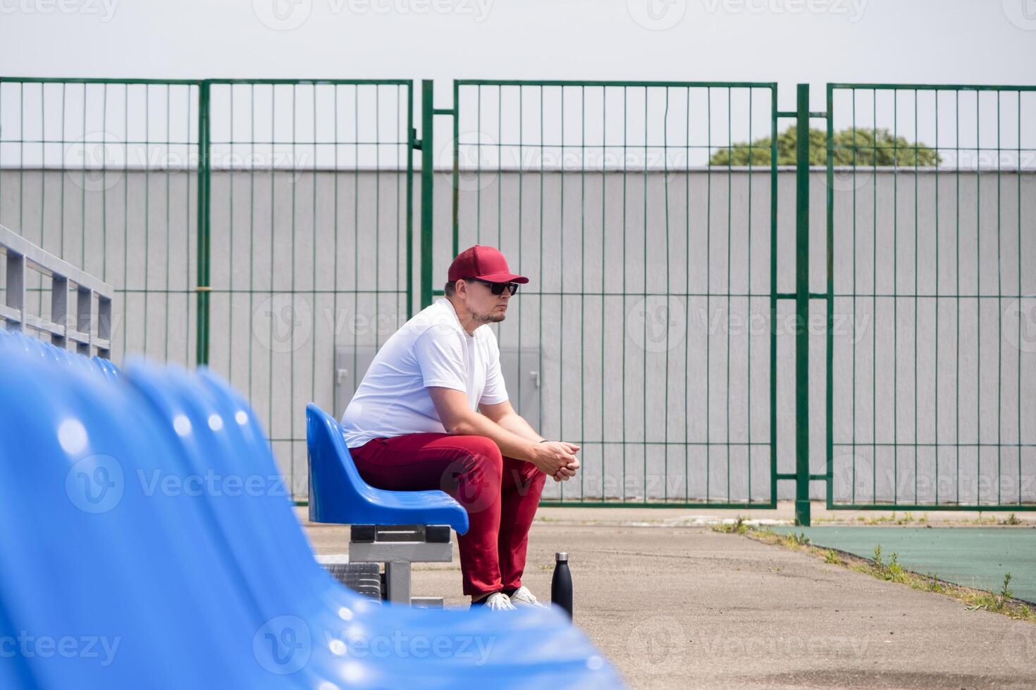 sportsman with a bottle of water sitting and resting at the seats at the stadium photo