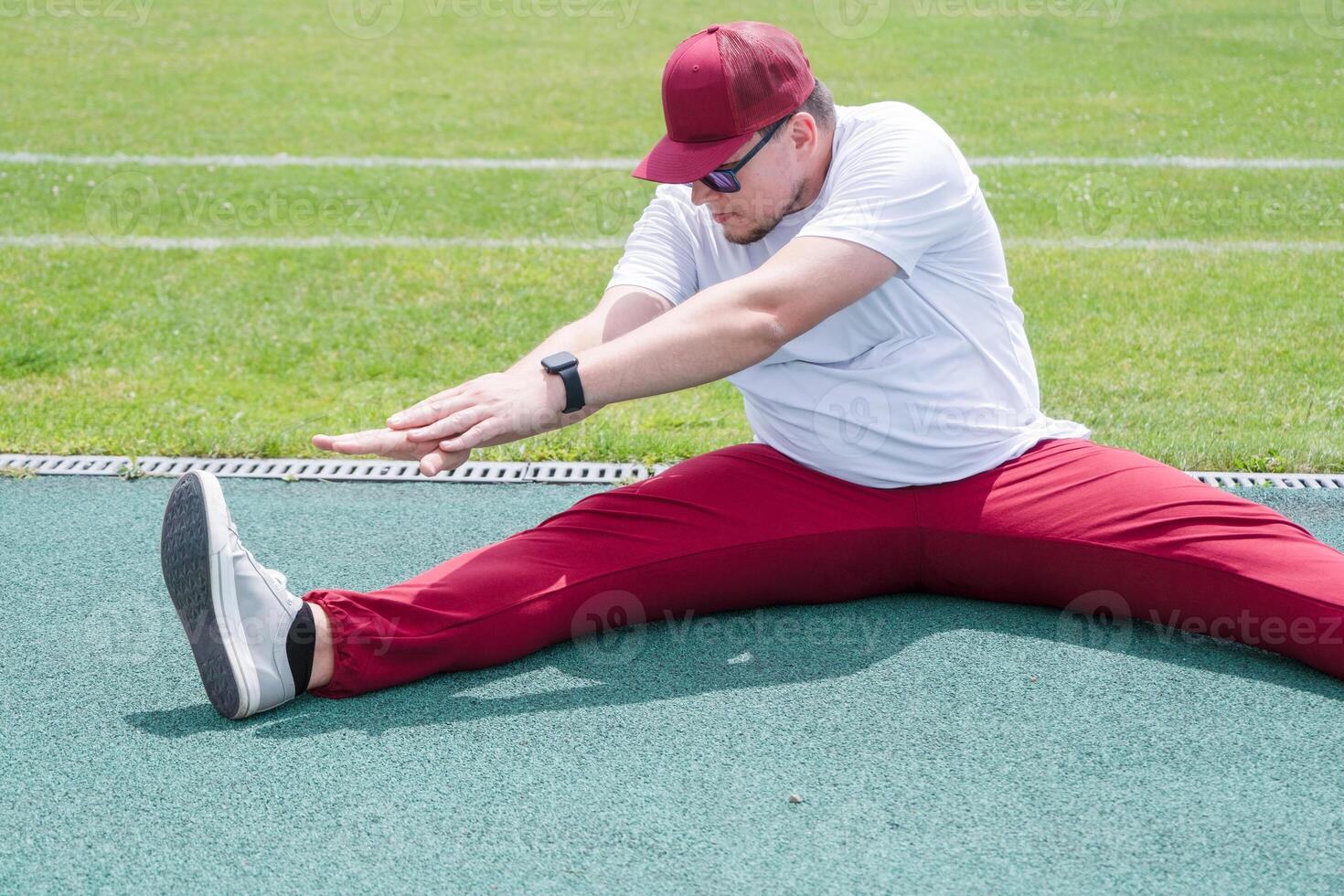 Athletic bearded man warms up before workout at the stadium photo