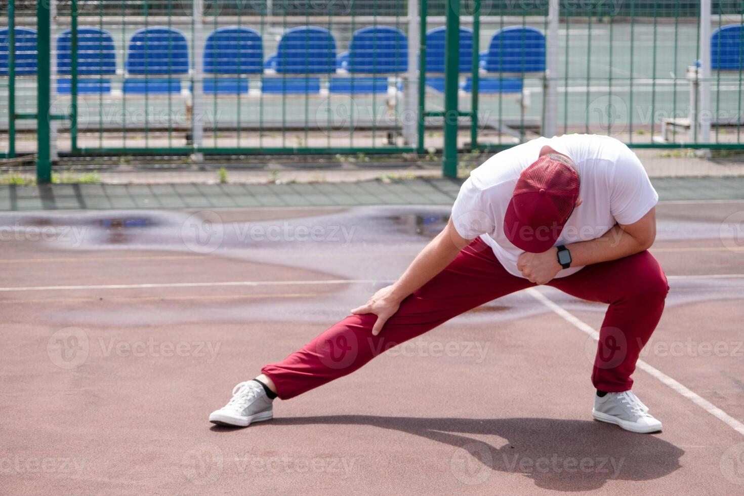 Athletic bearded man warms up before workout at the stadium photo