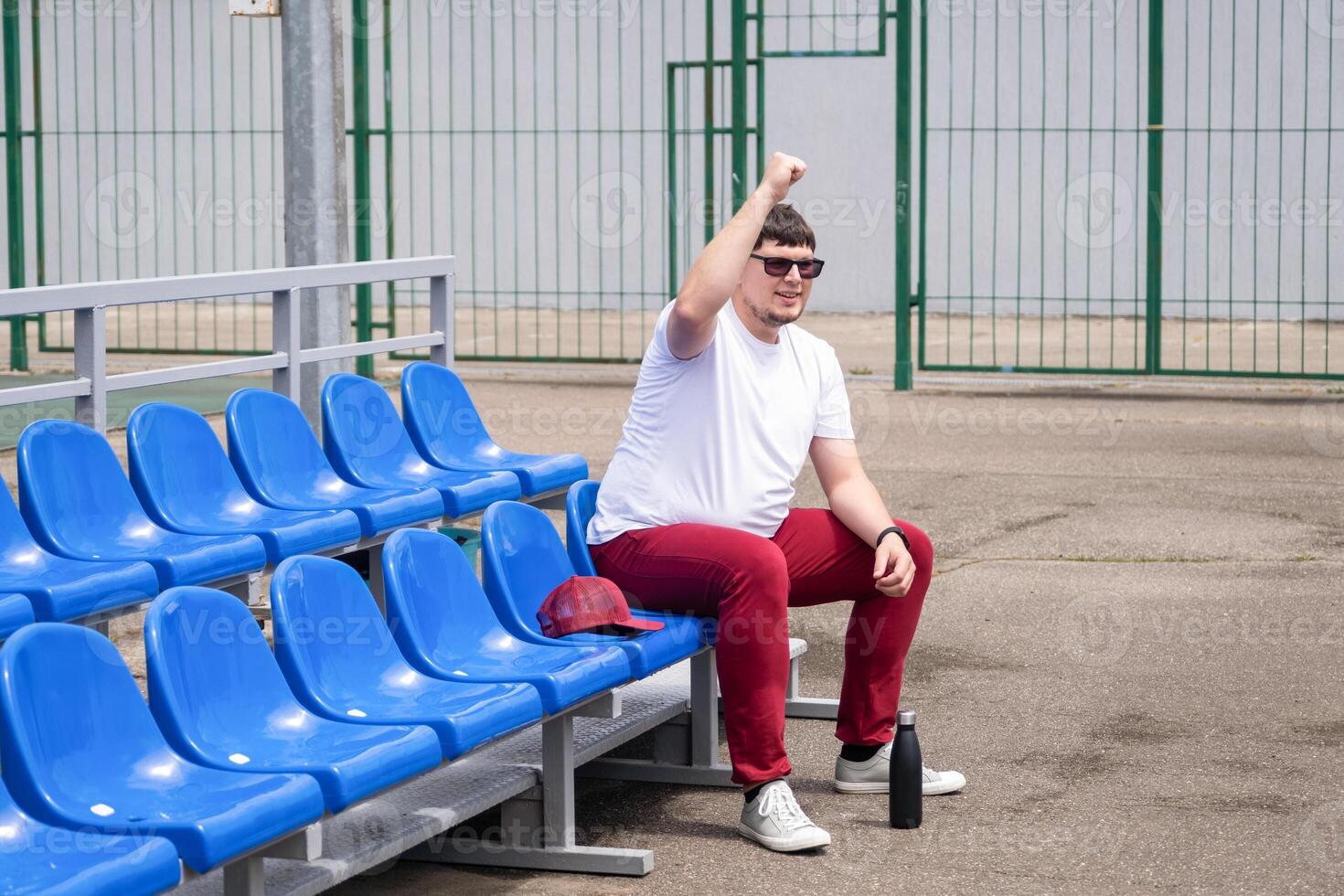 sportsman with a bottle of water sitting and resting at the seats at the stadium photo