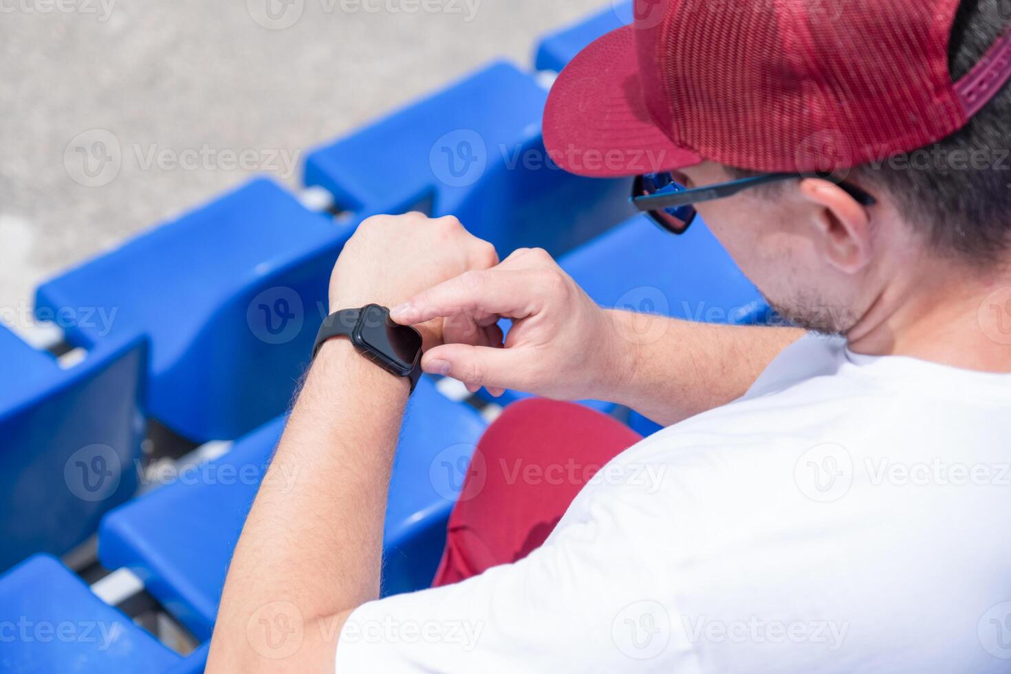 sportsman with a bottle of water sitting and resting at the seats at the stadium photo