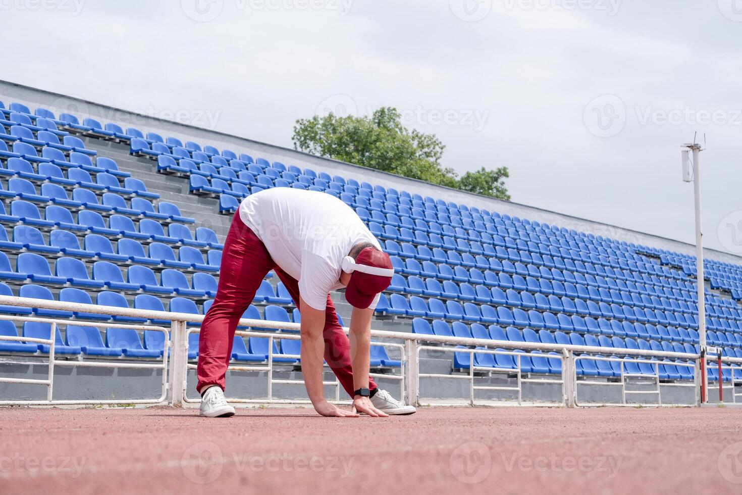 Athletic bearded man warms up before workout at the stadium photo