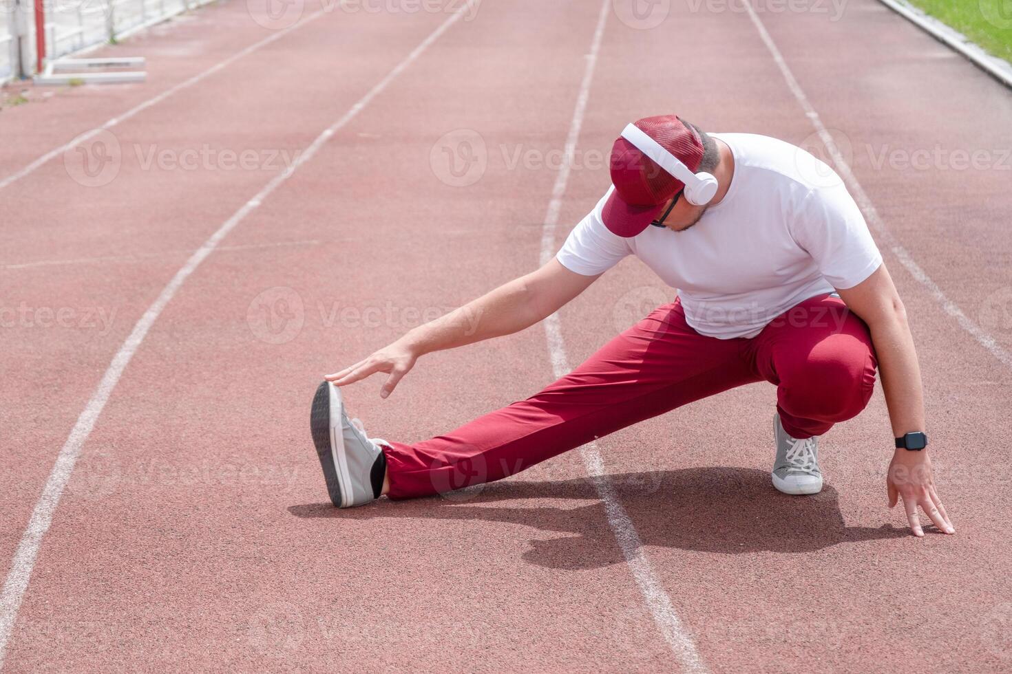 Athletic bearded man warms up before workout at the stadium photo