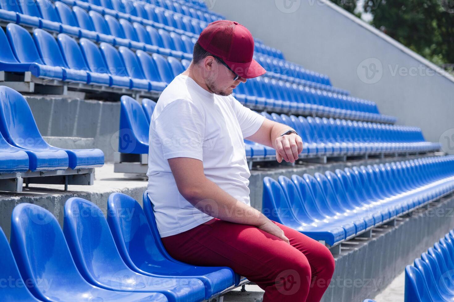 sportsman with a bottle of water sitting and resting at the seats at the stadium photo
