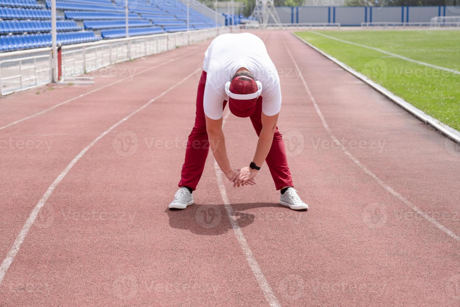 Athletic bearded man warms up before workout at the stadium photo