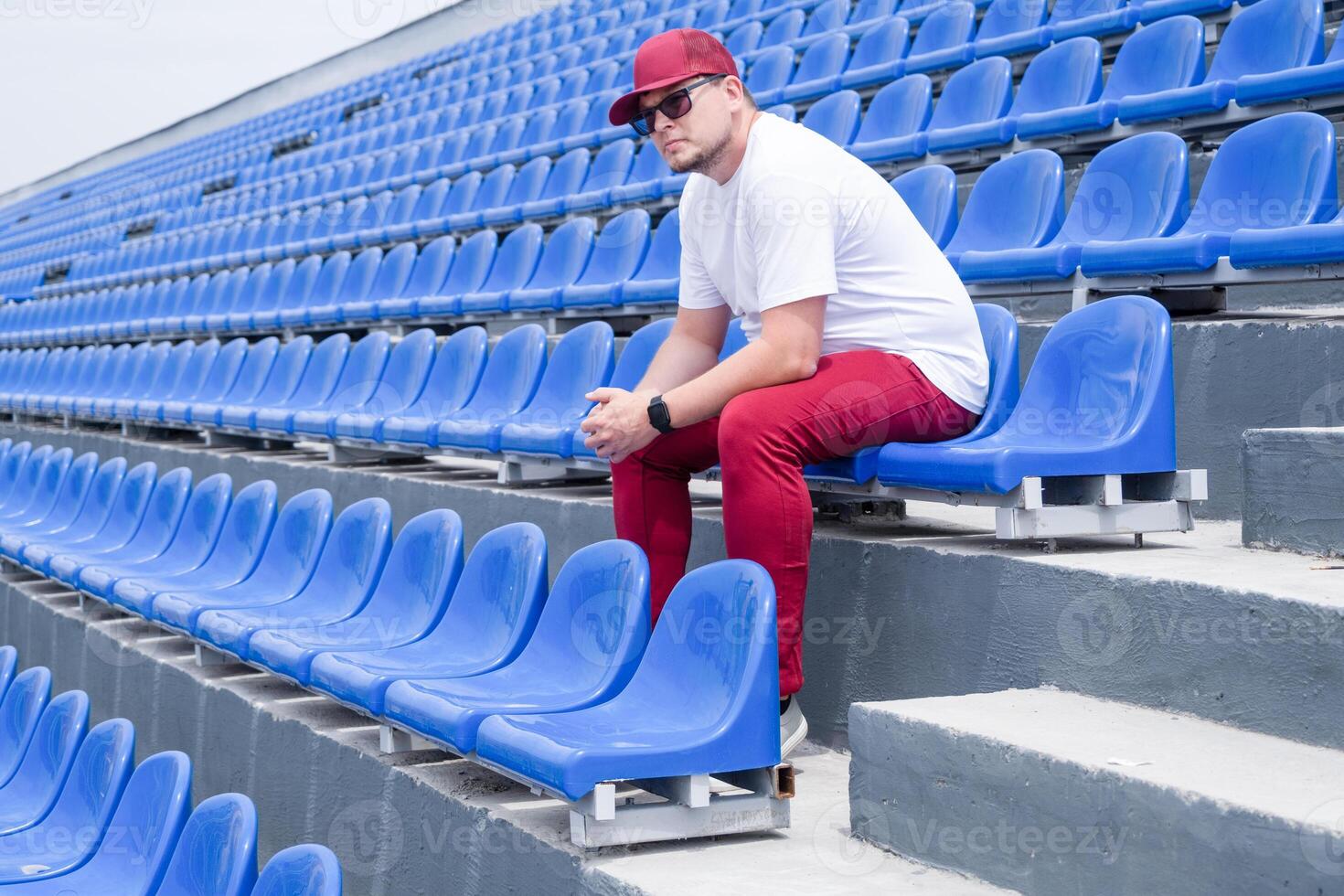 sportsman with a bottle of water sitting and resting at the seats at the stadium photo