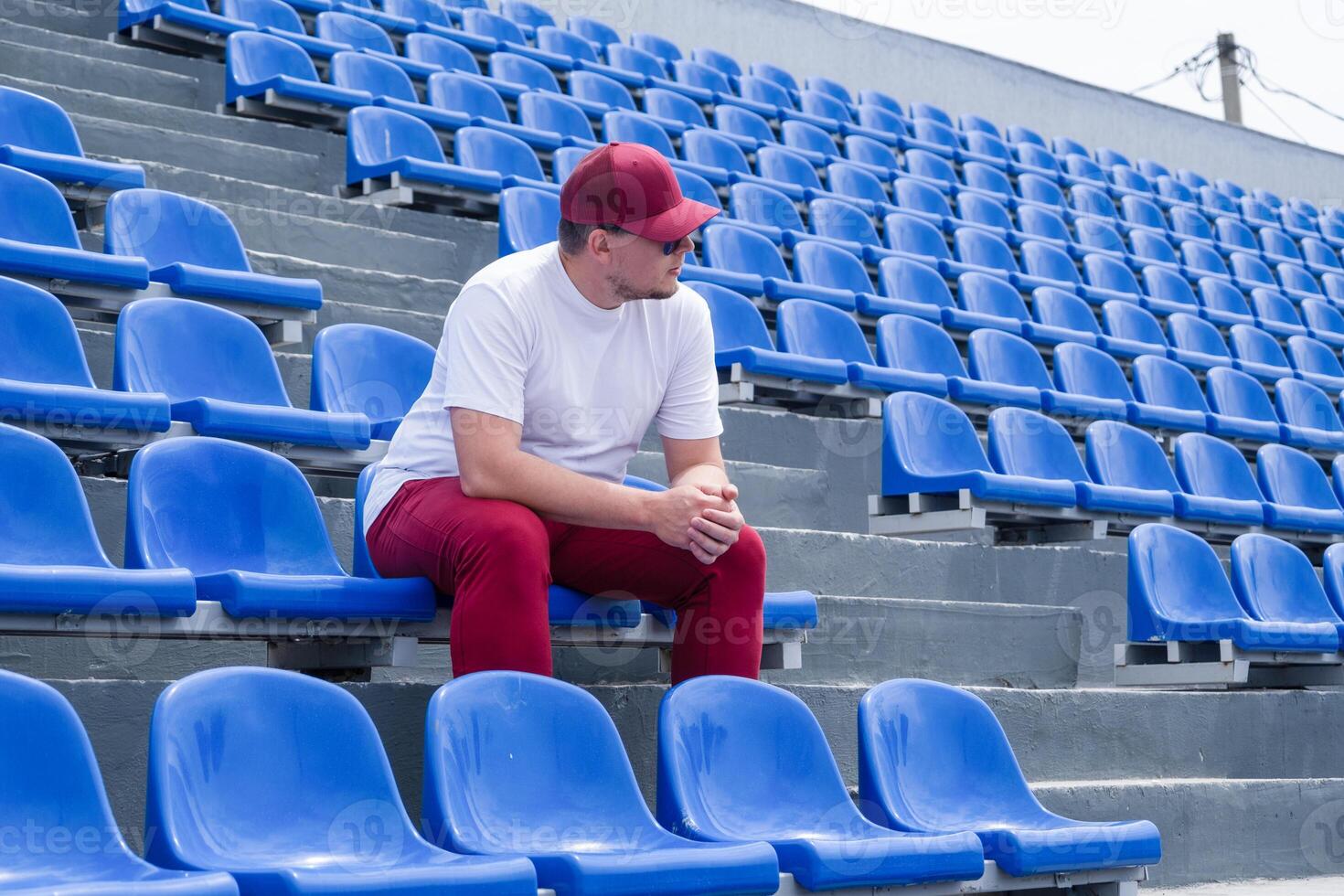 sportsman with a bottle of water sitting and resting at the seats at the stadium photo