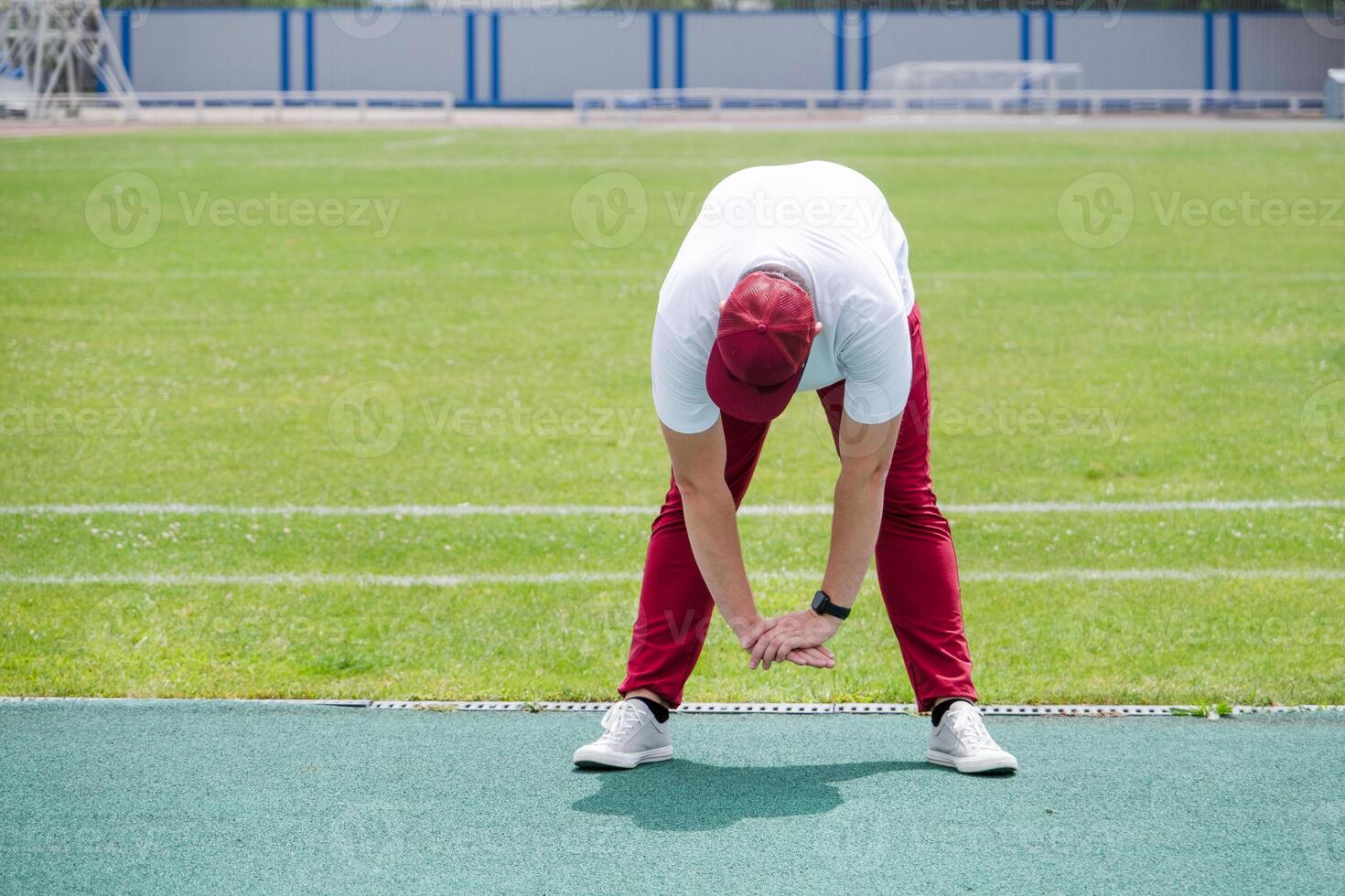 Athletic bearded man warms up before workout at the stadium photo