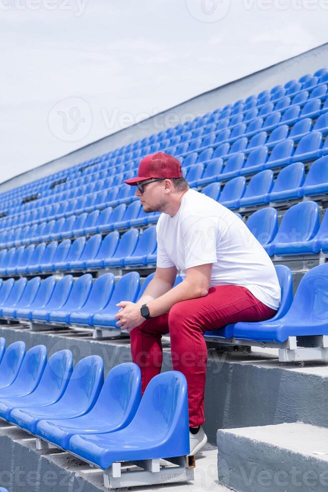 sportsman with a bottle of water sitting and resting at the seats at the stadium photo