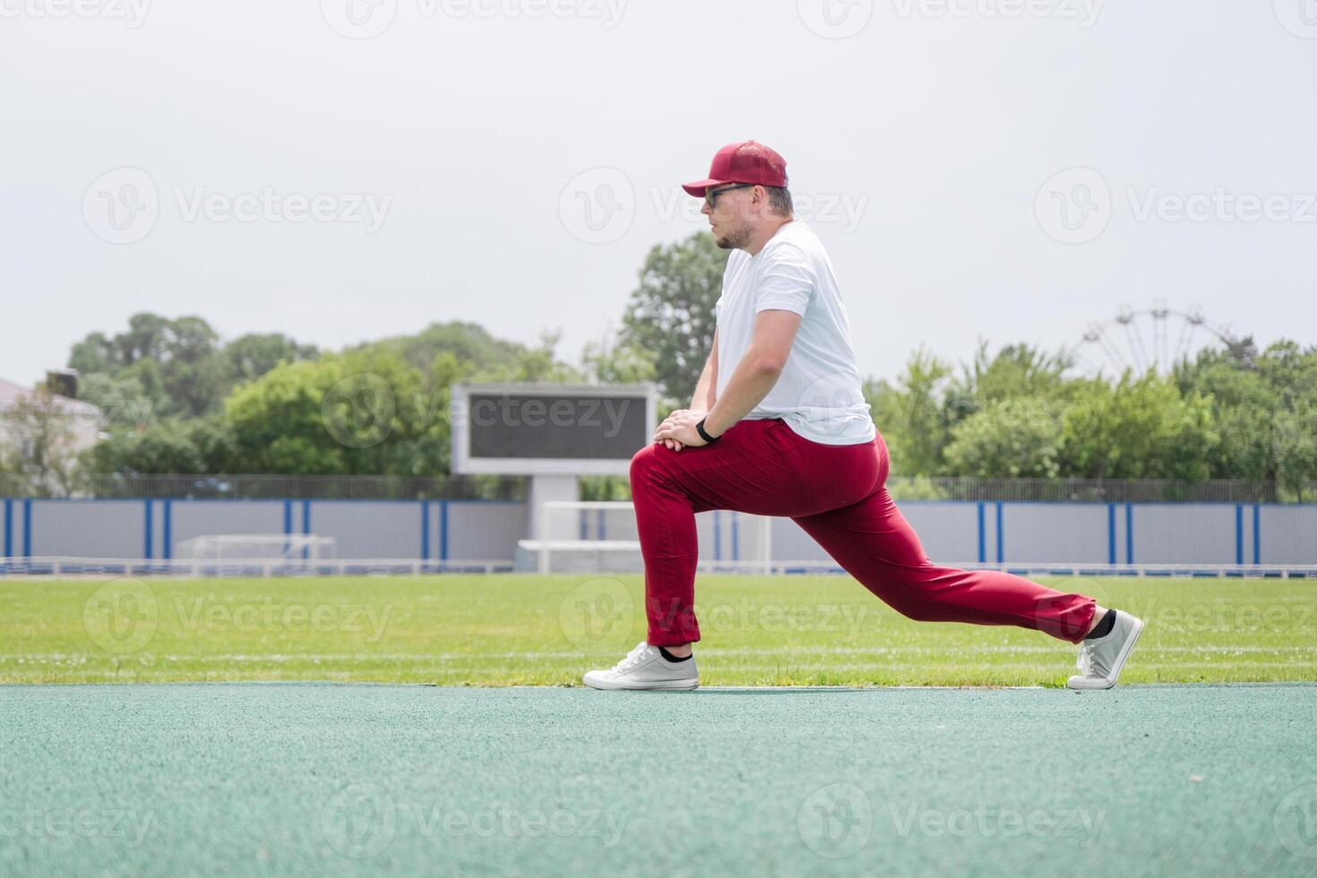 Athletic bearded man warms up before workout at the stadium photo