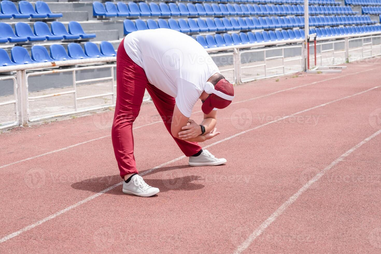 Athletic bearded man warms up before workout at the stadium photo