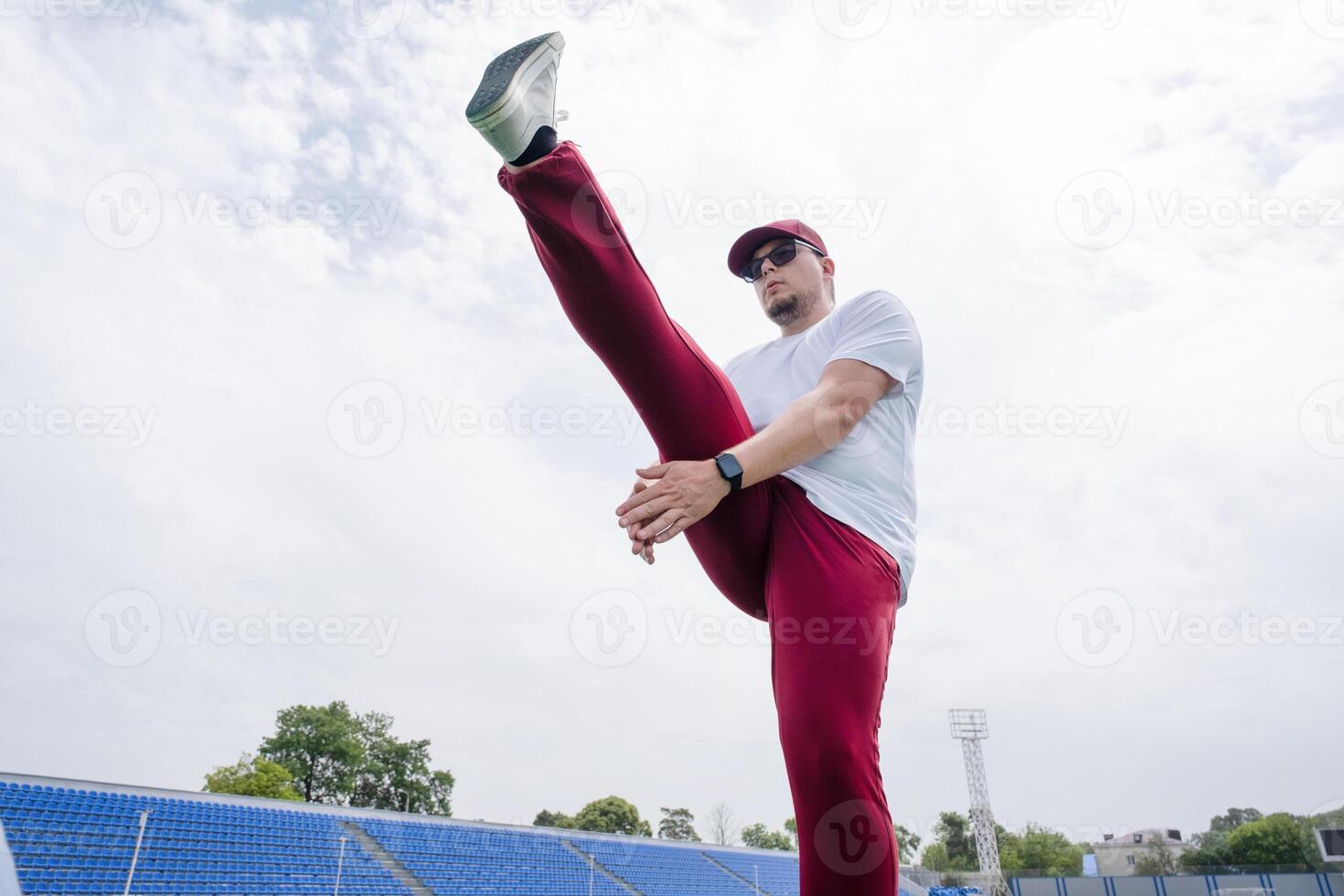 Athletic bearded man warms up before workout at the stadium photo