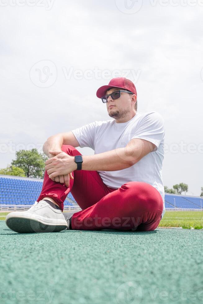 Athletic bearded man resting sitting at the stadium photo