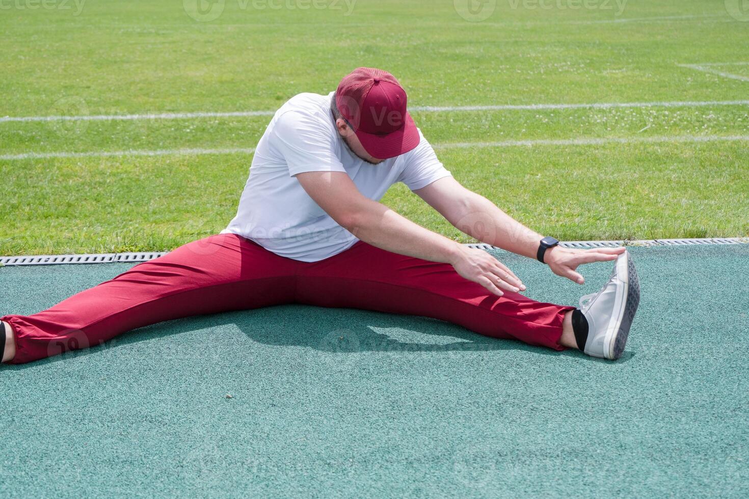 Athletic bearded man warms up before workout at the stadium photo