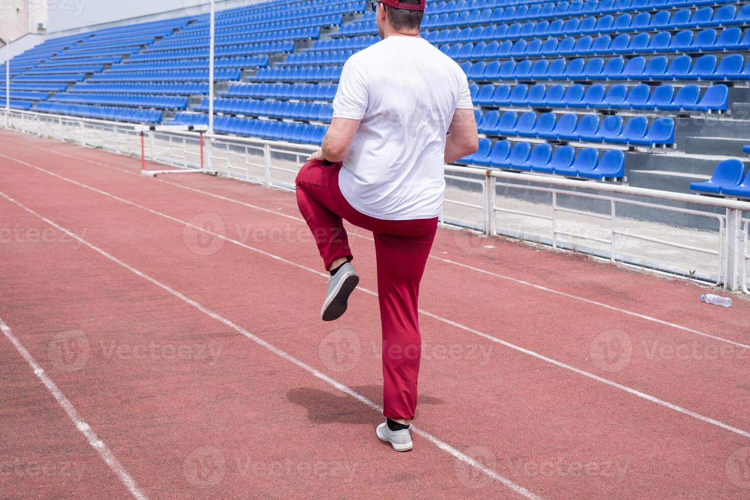 Athletic bearded man warms up before workout at the stadium photo