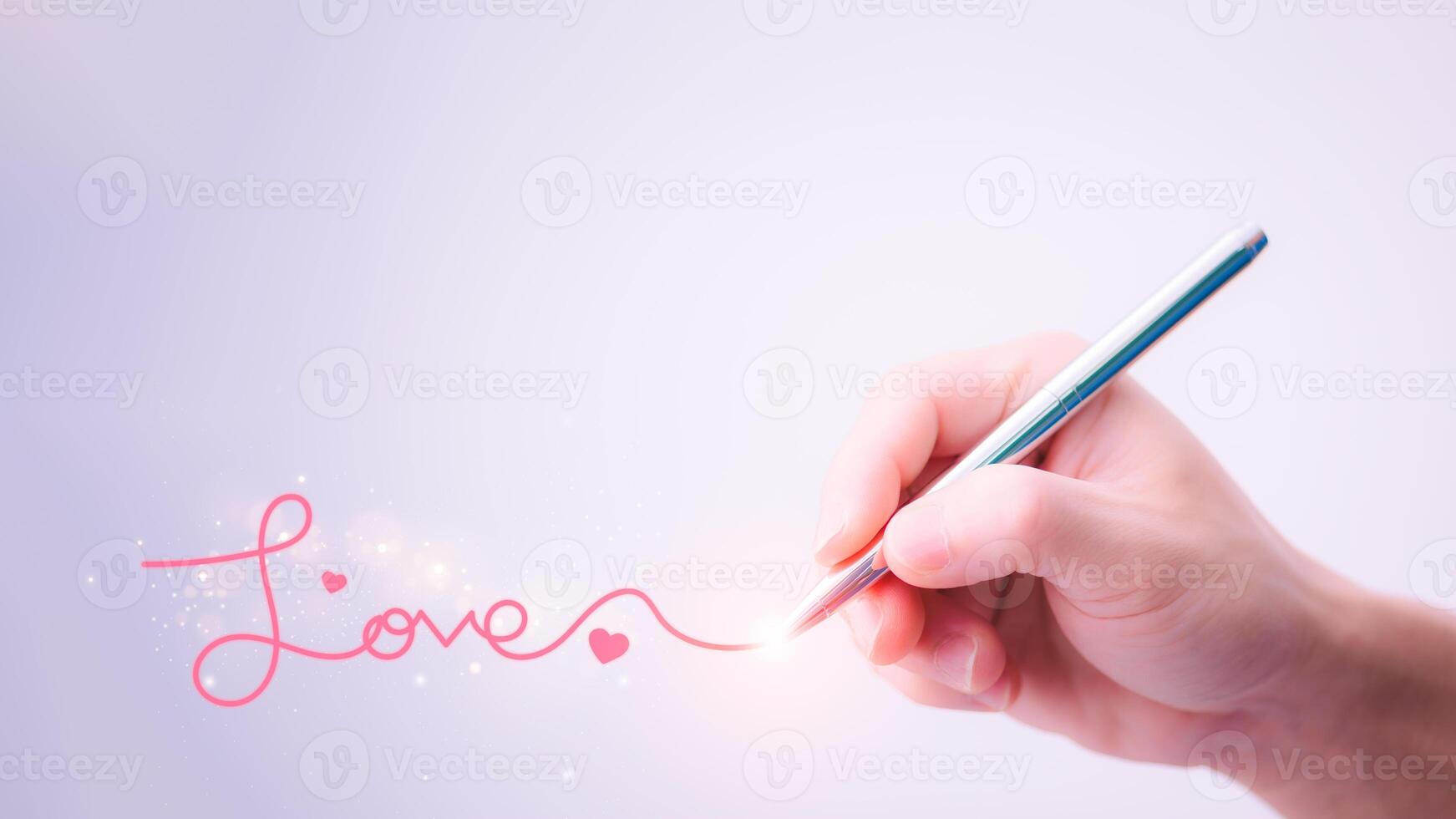 A man's hand holding a pen and writing the word love to convey pure love to a woman. Love ideas for Valentine's Day with sweet and romantic moments. photo