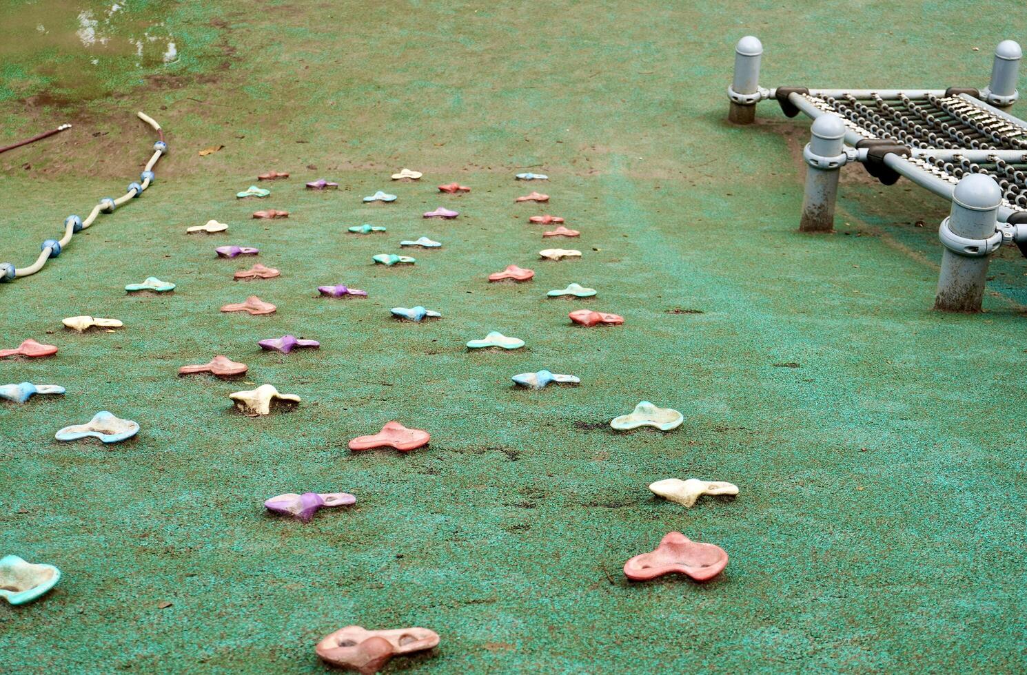 Children playground climbing rocks toy obstacle with net rope objects isolated on horizontal ratio green ground outdoor flooring background. photo