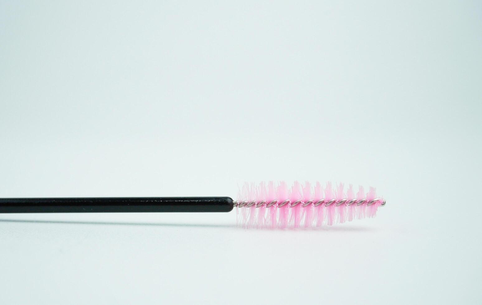 Mascara eyelash brush with black and pink color beauty tool object isolated on horizontal ratio white copy spaced background. photo