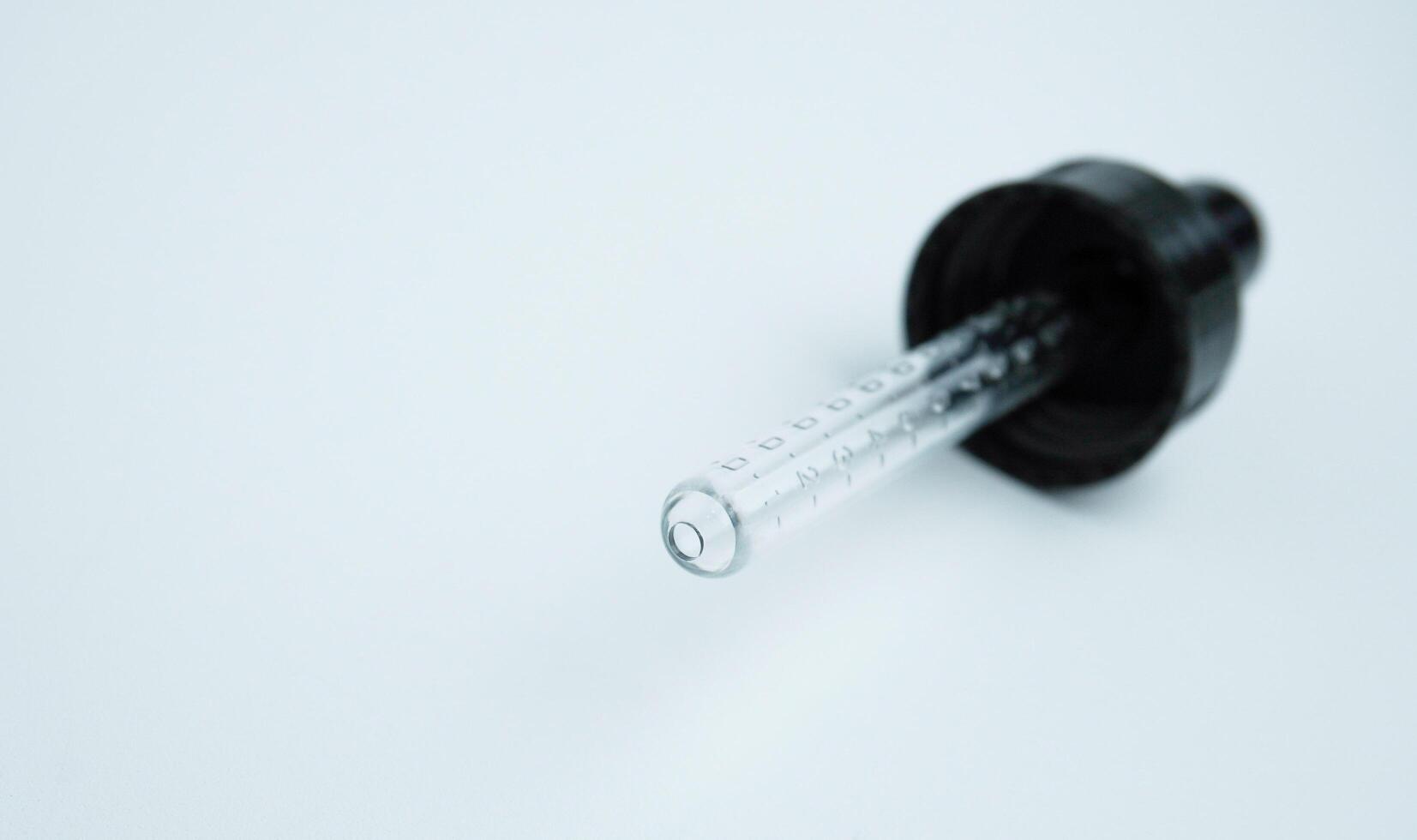 One single pipette lid pump with rubber and clear glass material. Small object photography isolated on horizontal ratio white background. photo