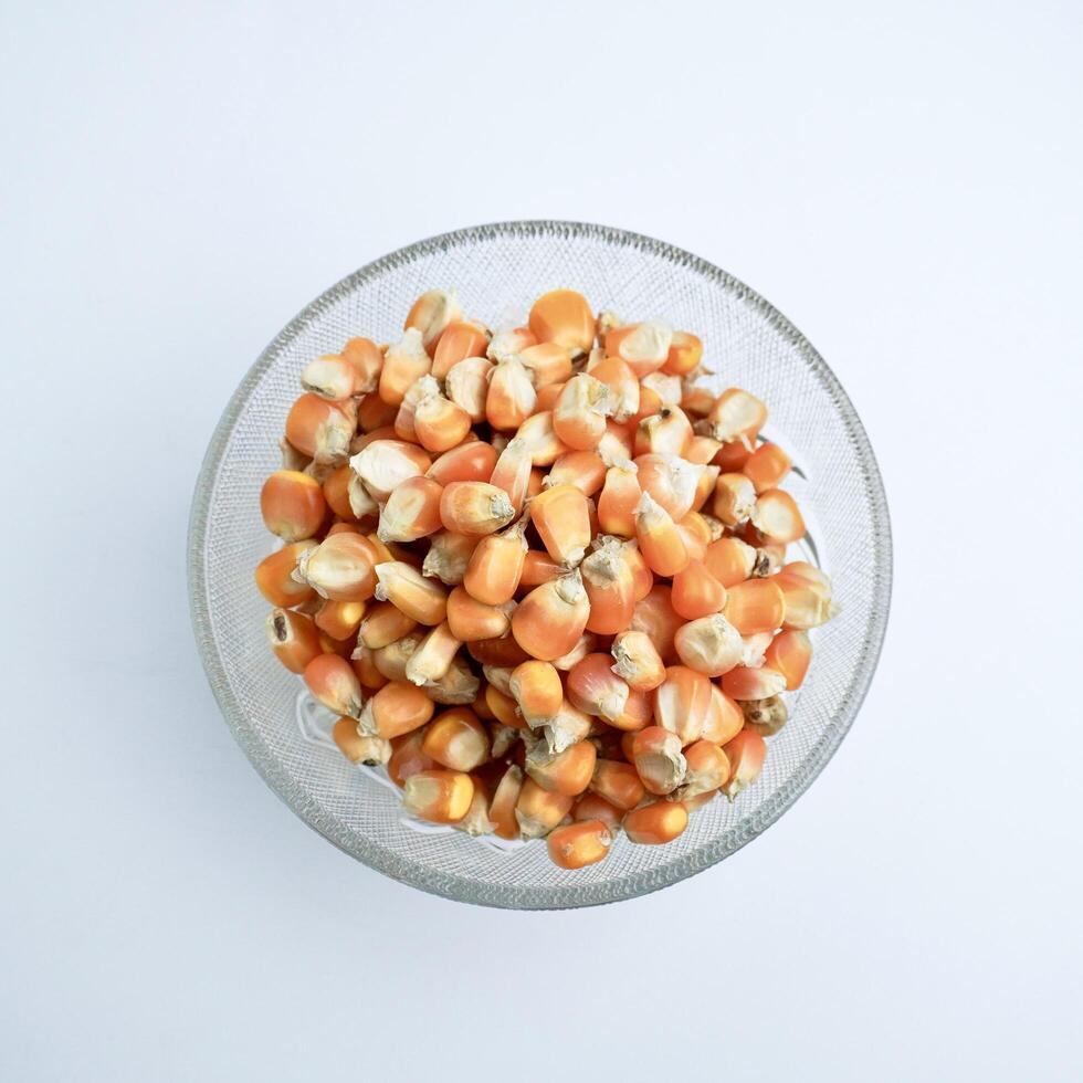 Groups of dry yellow corns in glass bowl food ingredients photography isolated on above top angle view horizontal ratio white background. photo