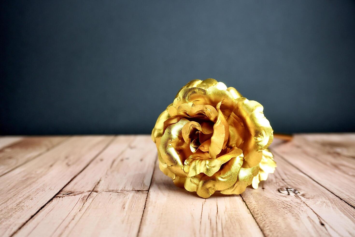 Gold rose flower petal from front view. Object photography isolated on horizontal ratio wooden surface background. photo