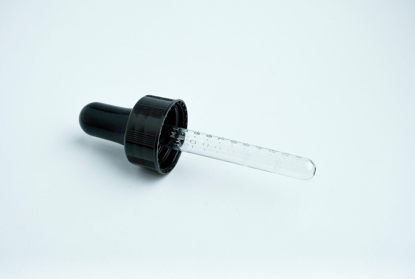 One single pipette lid pump with rubber and clear glass material. Small object photography isolated on horizontal ratio white background. photo
