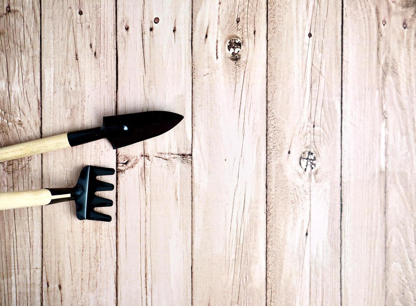 Small shovel and fork rake gardening tool with wooden handle and metal material. Object photography isolated on horizontal ratio wooden surface background. photo