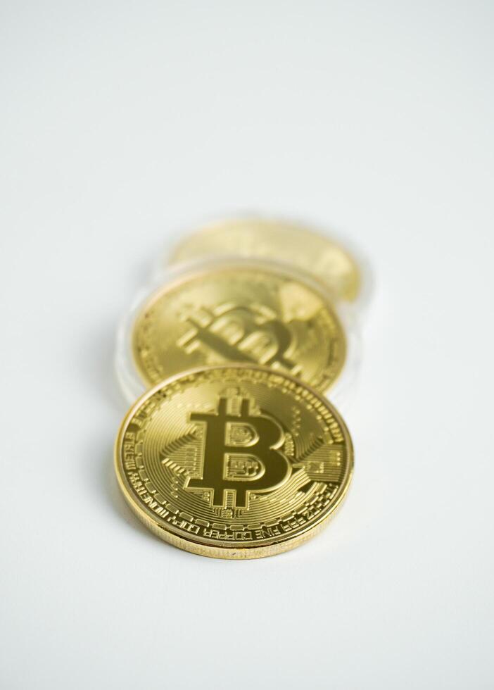 Three gold bitcoin cryptocurrency isolated on vertical white background. photo