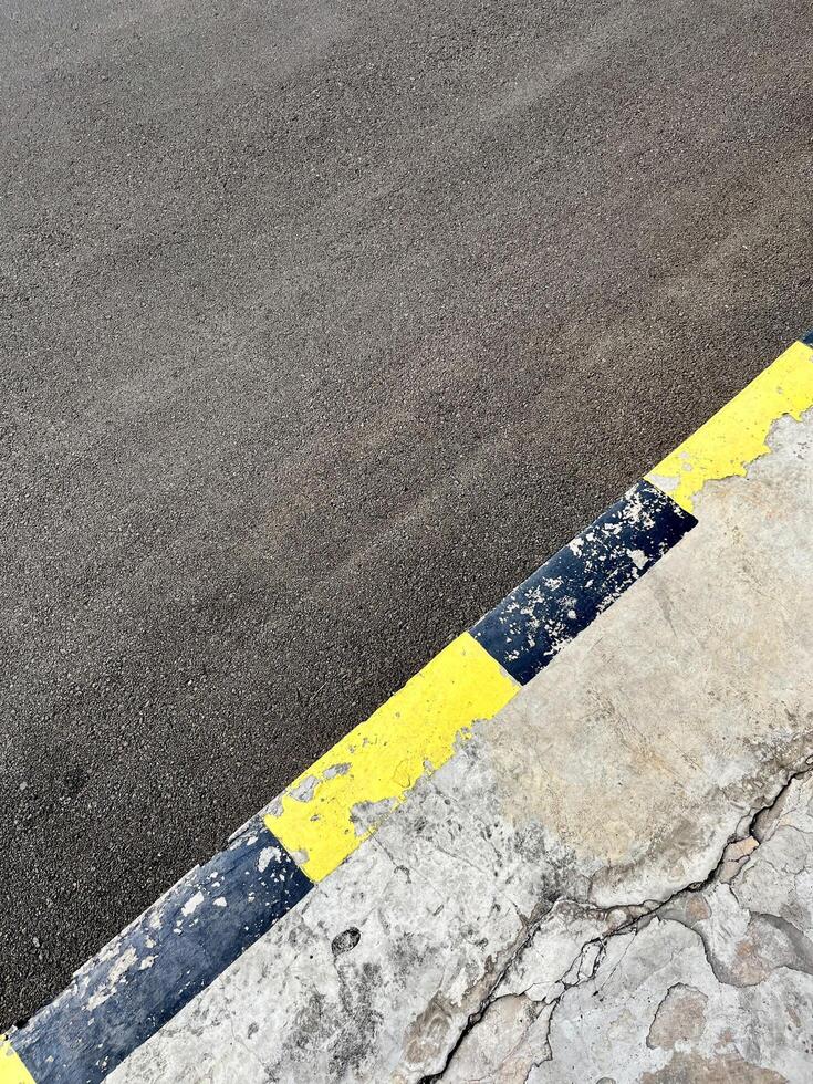 Gray asphalt road and cracked stone cement pavement with black and yellow paint stripes isolated on vertical ratio background. photo